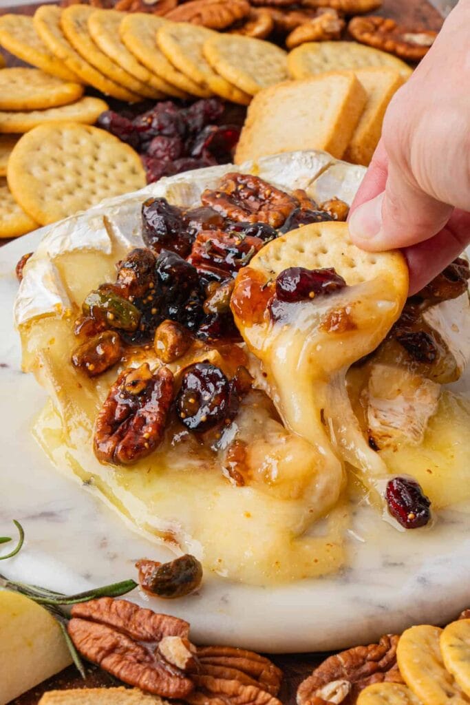 Baked brie on a marble serving plate with crackers on the side.