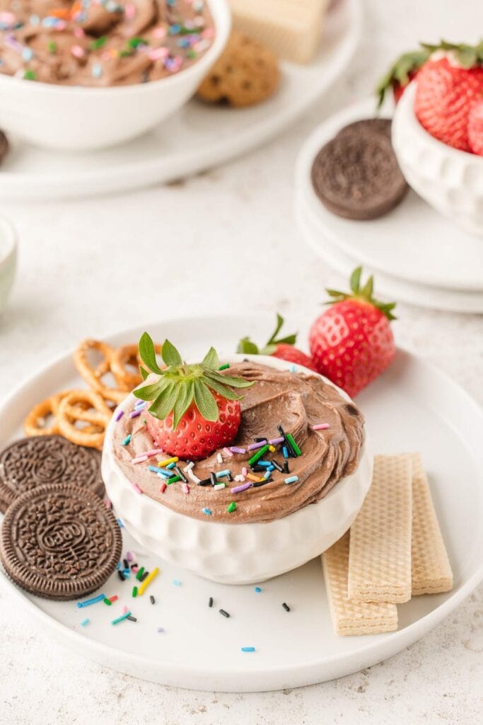 Creamy brownie batter dip in a bowl topped with a fresh strawberry.