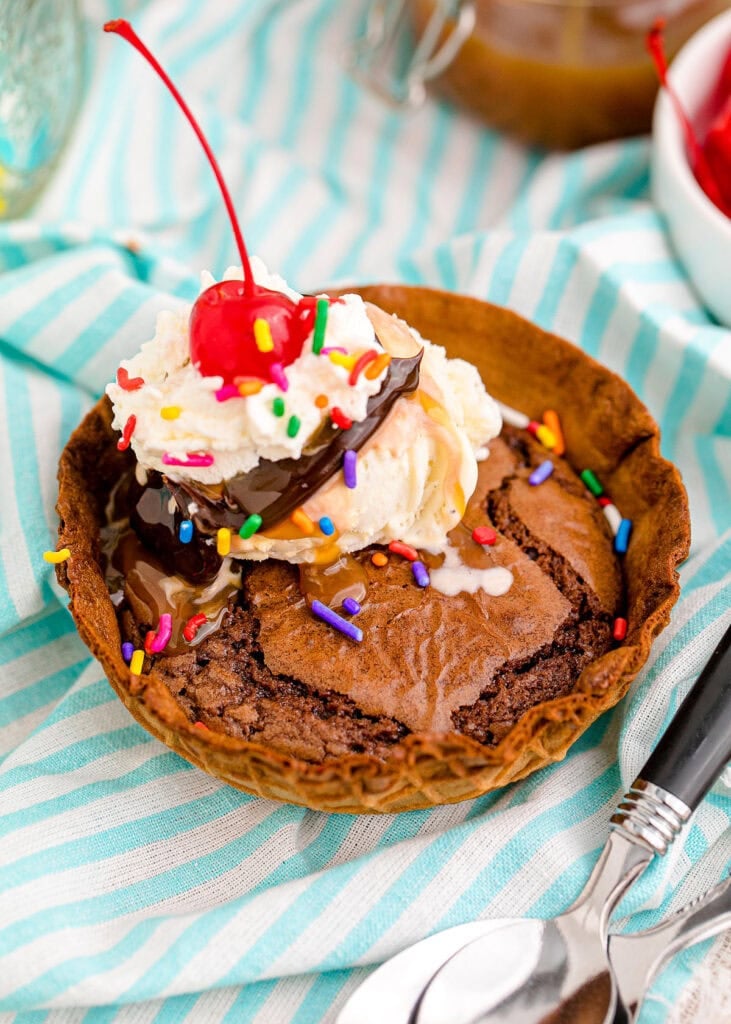Brownie sundae waffle bowls topped with ice cream and a cherry.
