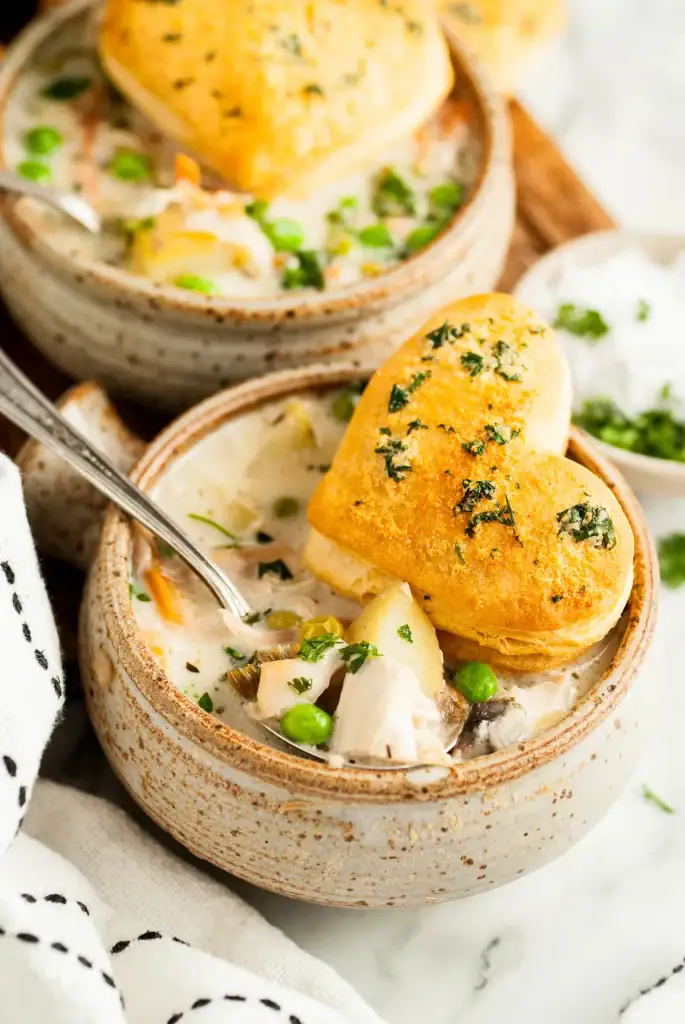 Chicken pot pie soup with heart-shaped biscuits in a bowl.