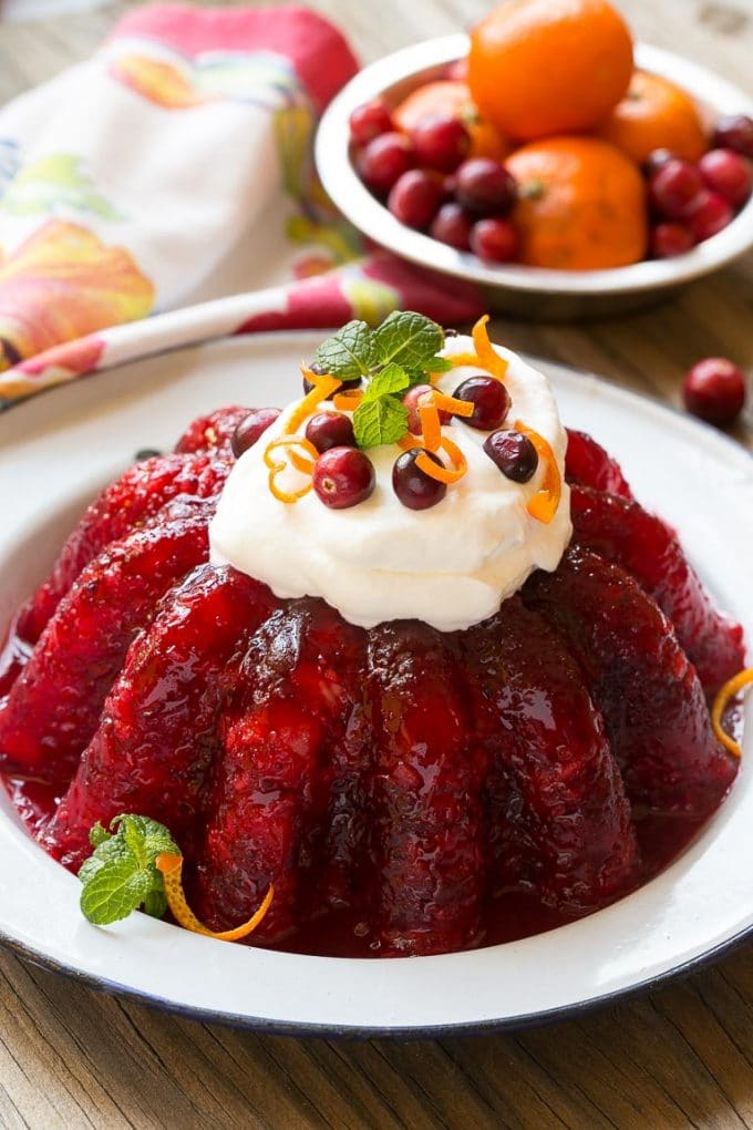Cranberry pineapple gelatin mold topped with whipped cream and cranberries.