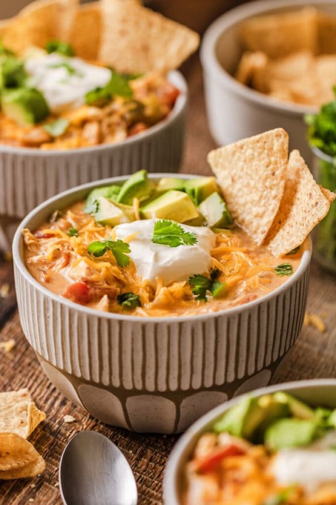 Creamy chicken fajita soup topped with avocado and sour cream in a bowl.