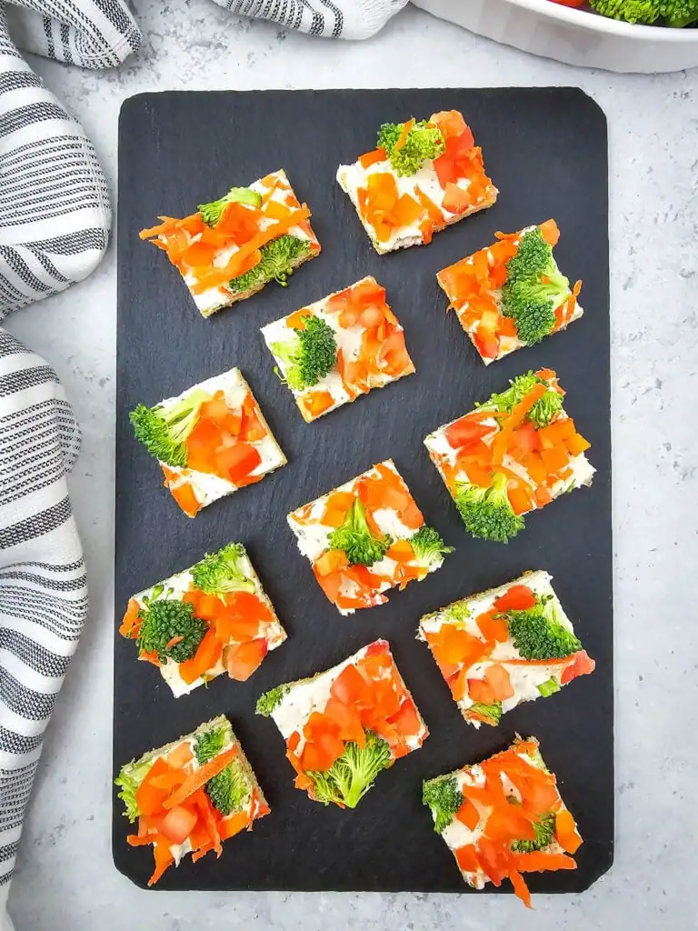 Crescent roll veggie pizza on a slate board.