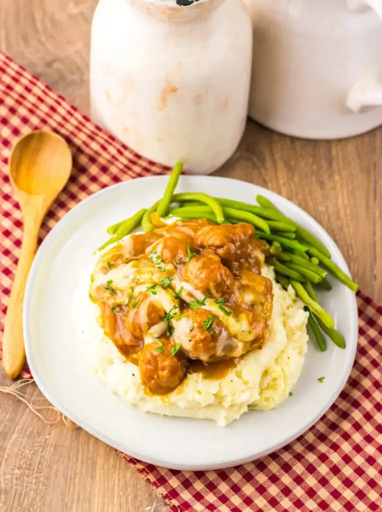 Crockpot French onion meatballs over mashed potatoes on a plate.