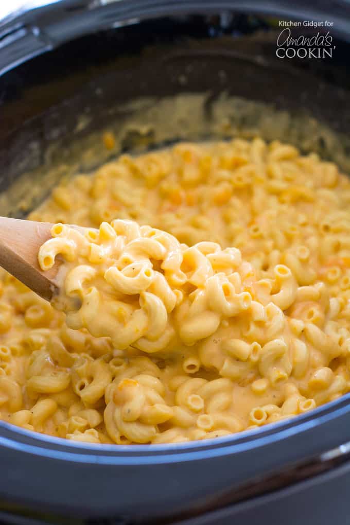 Crockpot macaroni and cheese on a wooden spoon.