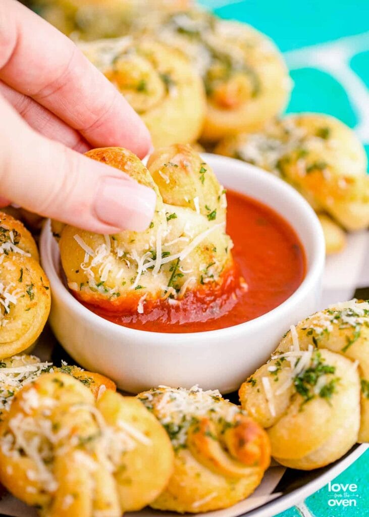 Garlic knots dipped in marinara sauce.