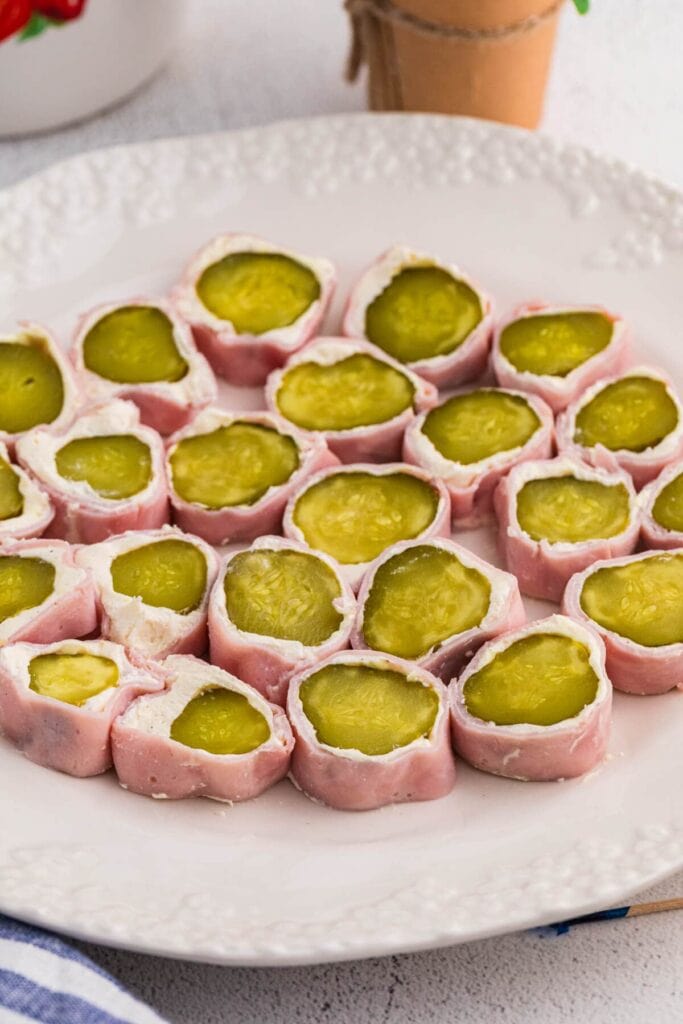 Ham and pickle roll ups on a plate.