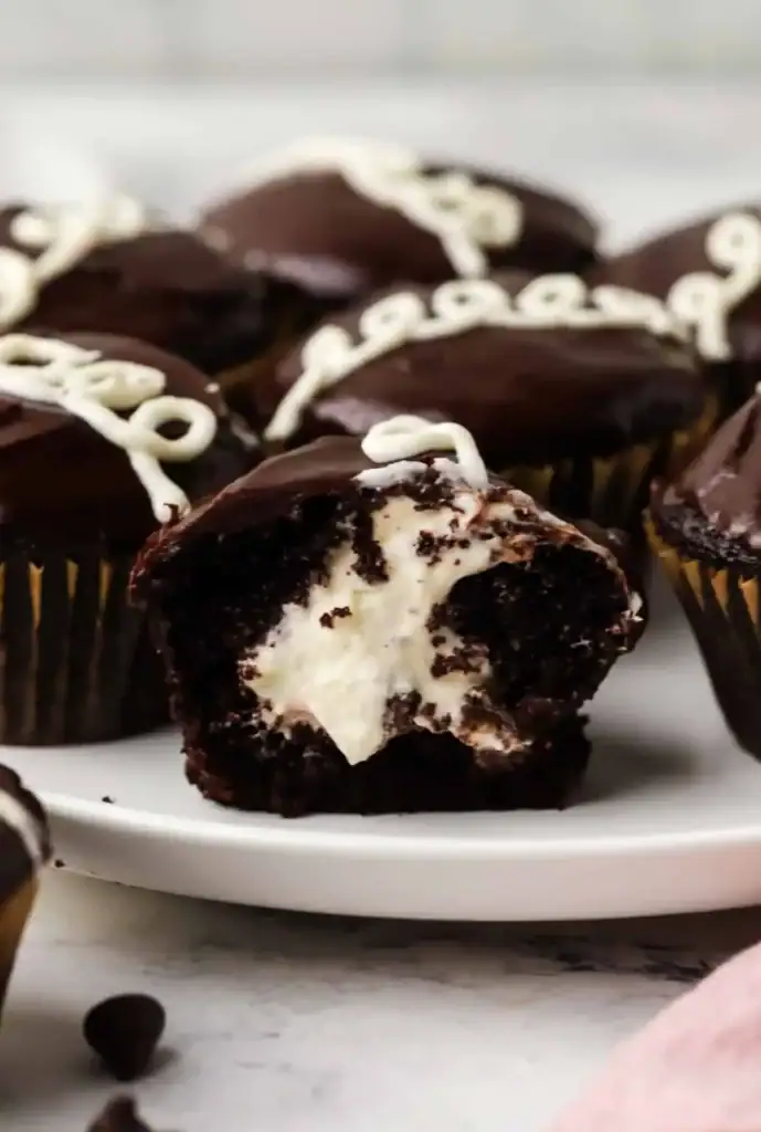 Homemade Hostess chocolate cupcakes with white icing swirls on a plate.