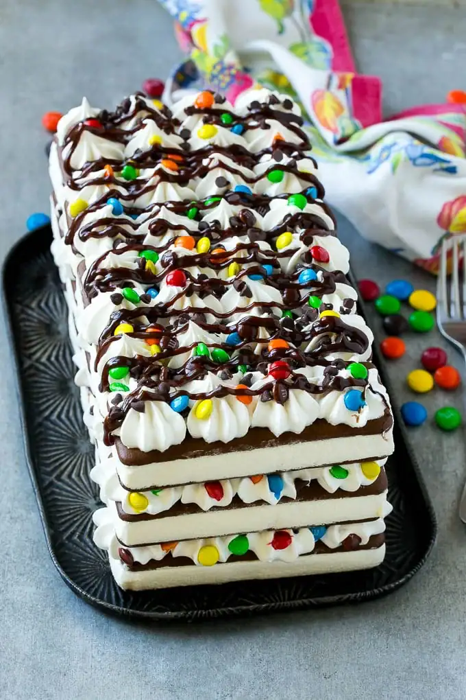 Ice cream sandwich cake topped with whipped cream and chocolate drizzle.