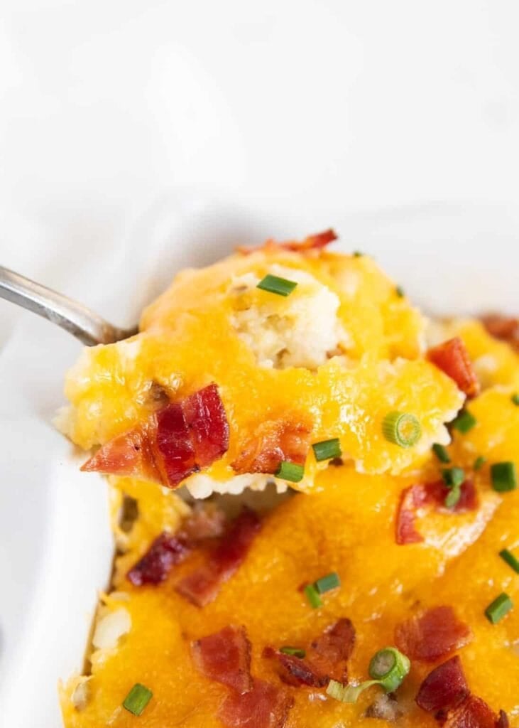 Close-up of loaded baked potato casserole on a spoon.