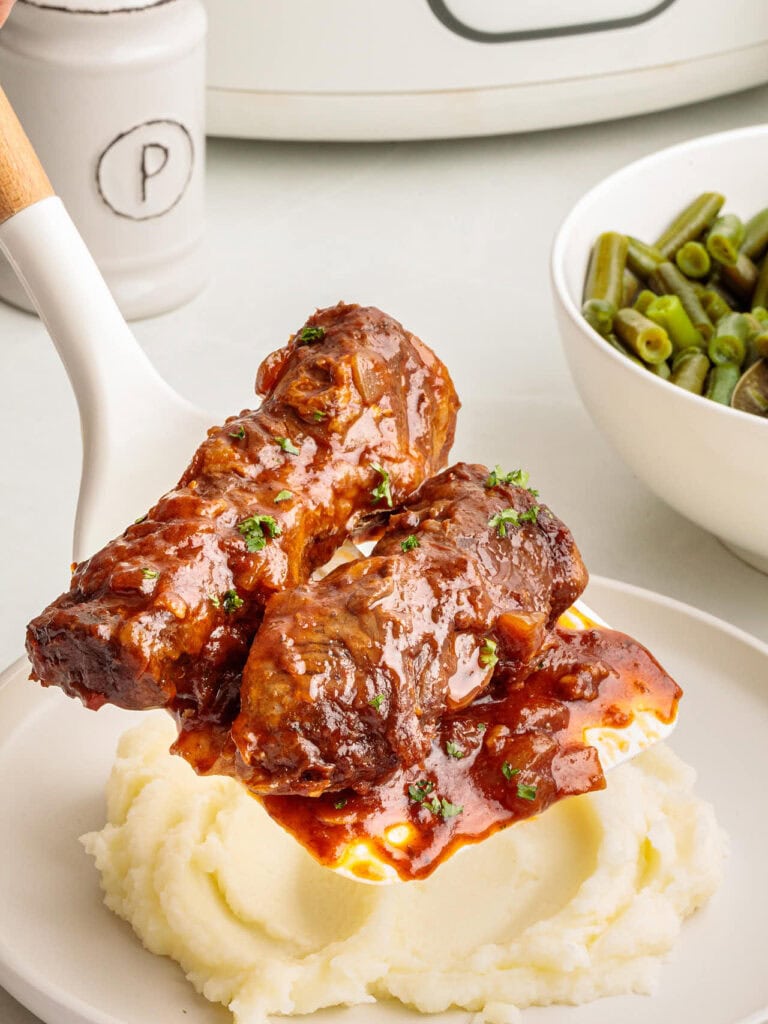 Slow cooker beef short ribs on a spatula.
