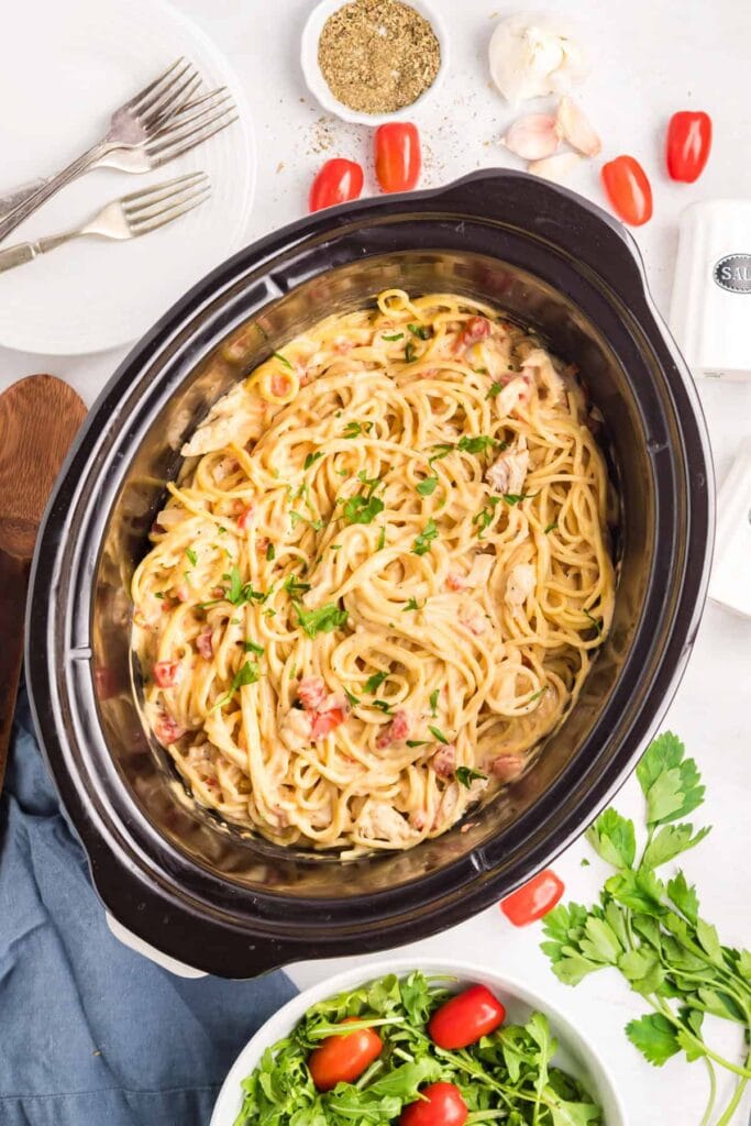 Slow cooker chicken spaghetti with creamy sauce and parsley.