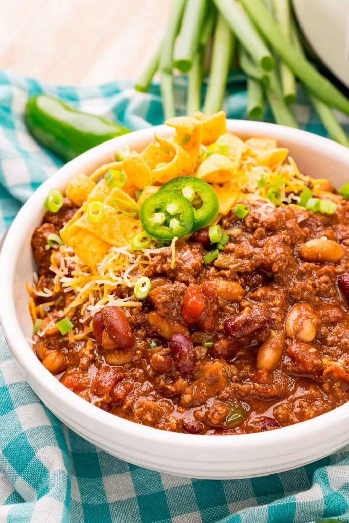 Slow cooker chili topped with corn chips and jalapeños in a bowl.