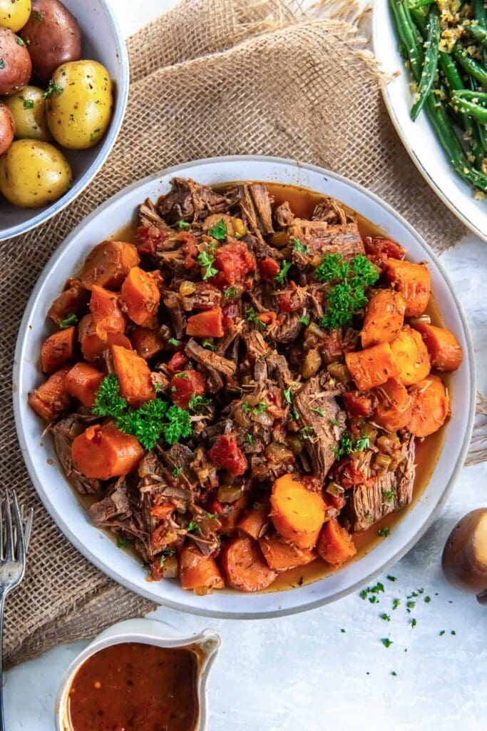 Slow cooker Italian pot roast with carrots and potatoes on a plate.