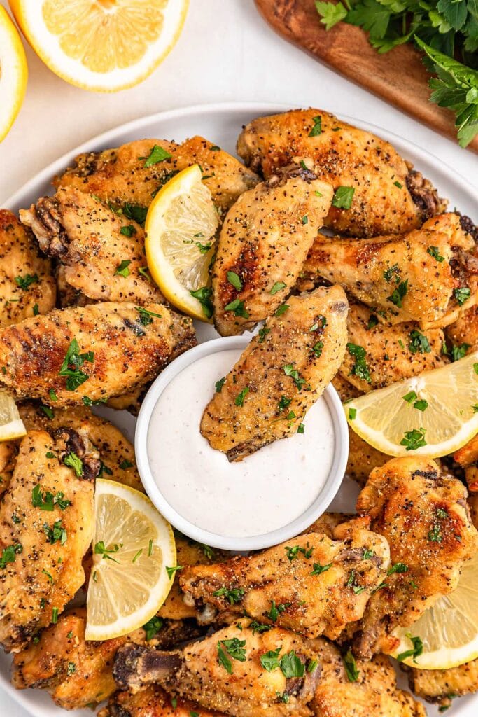 Slow cooker lemon pepper wings with dipping sauce on a plate.