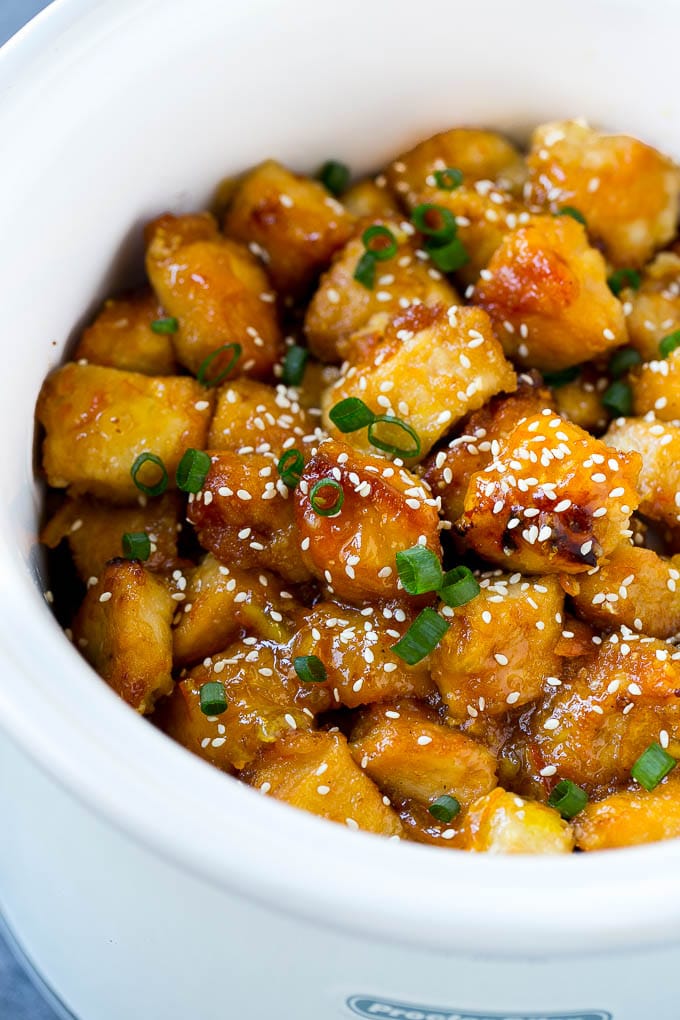Slow cooker orange chicken with sesame seeds and green onions.