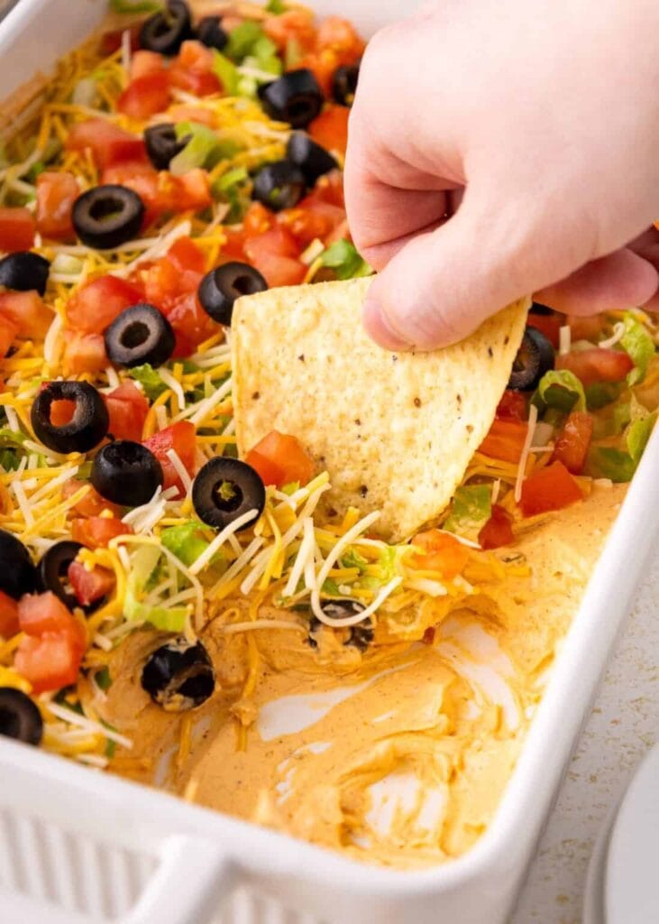 Taco dip with toppings in a baking dish.