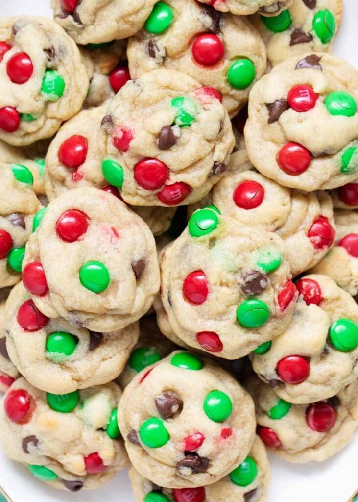 Thick golden cookies with red-green candy pieces and chocolate chips piled together for holiday styling.