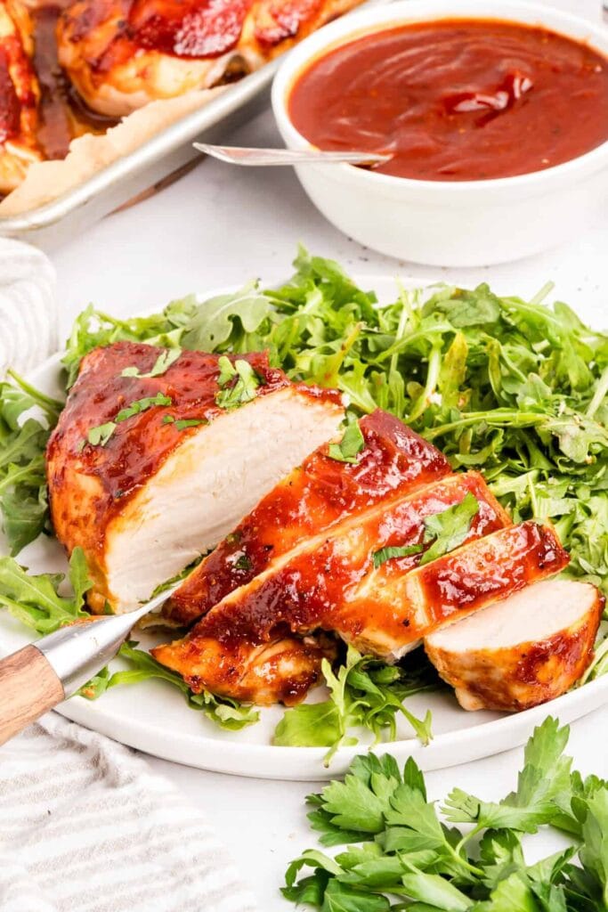 Baked BBQ chicken on a plate with greens.