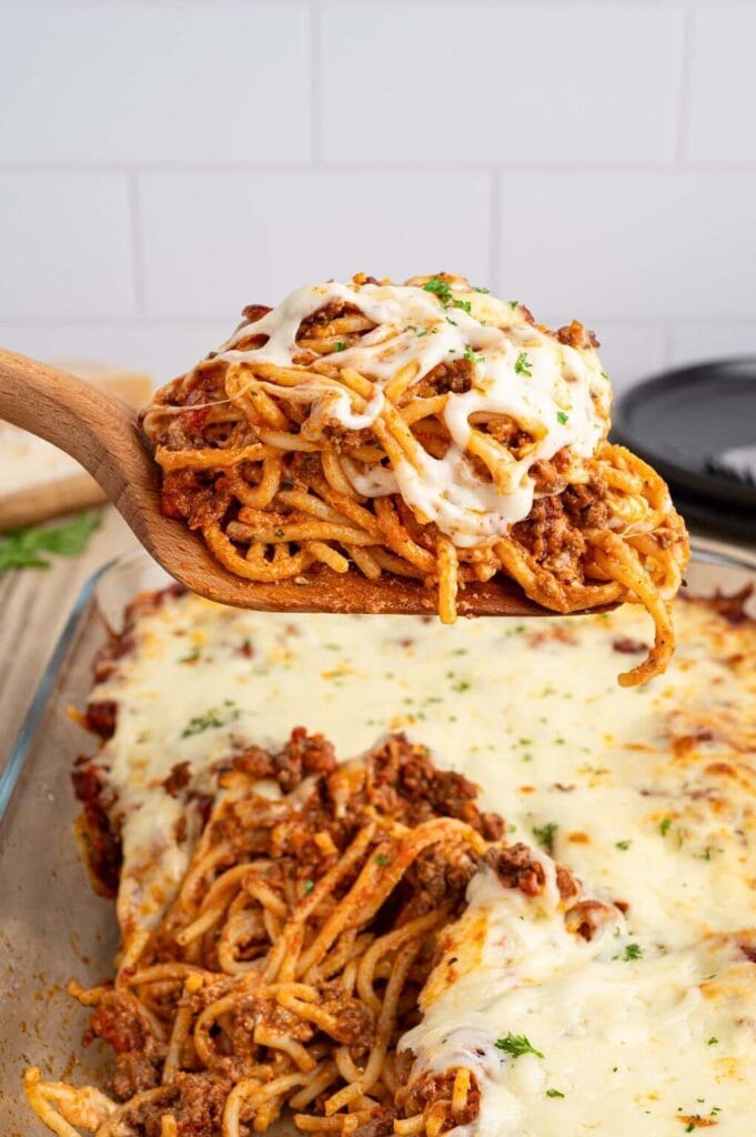 Baked spaghetti with cream cheese on a wooden spoon.