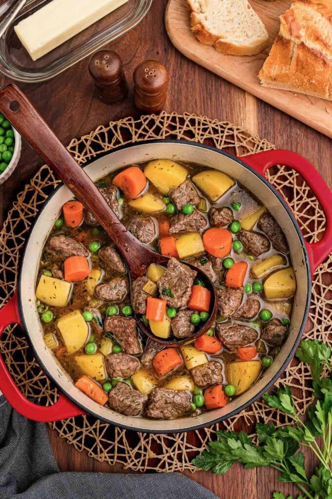 Beef stew with potatoes, carrots, and peas in a pot.