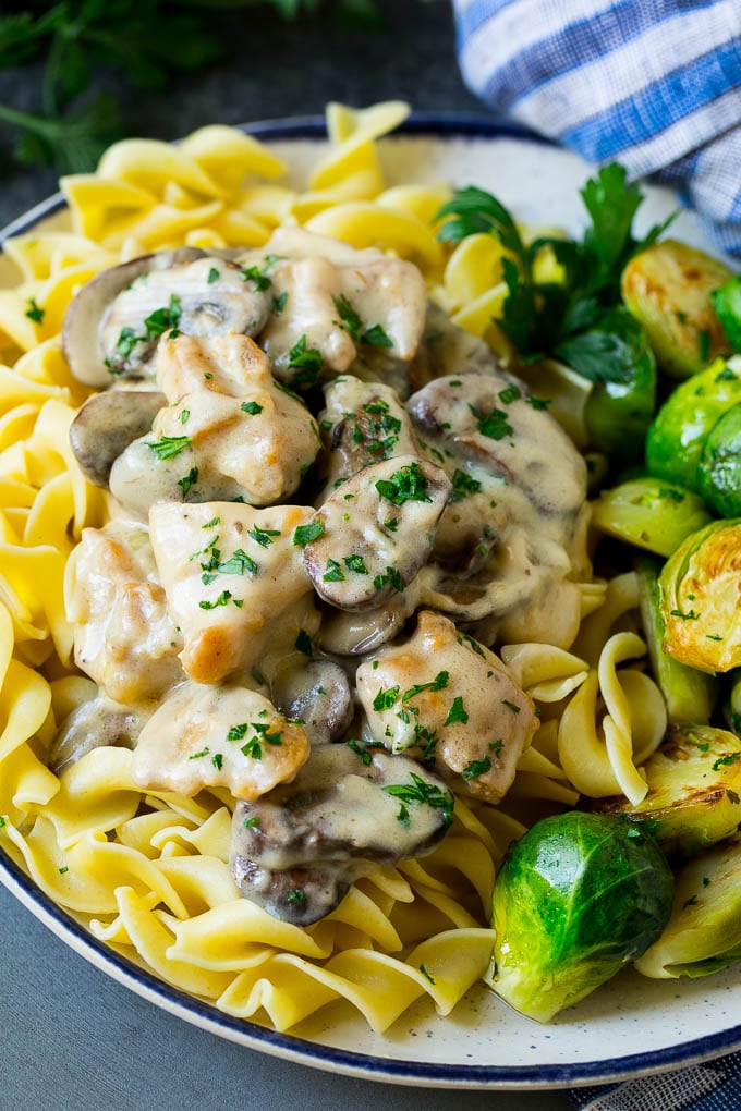 Chicken stroganoff with egg noodles and Brussels sprouts on a plate.