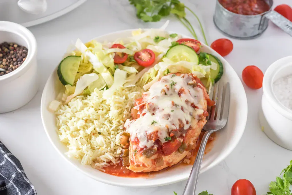 Crockpot salsa chicken with rice and salad on a plate.