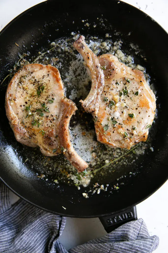 Garlic butter pork chops in a skillet.