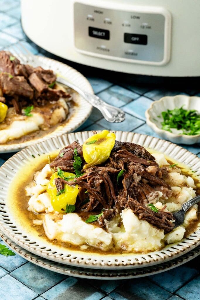 Mississippi pot roast over mashed potatoes on a plate.