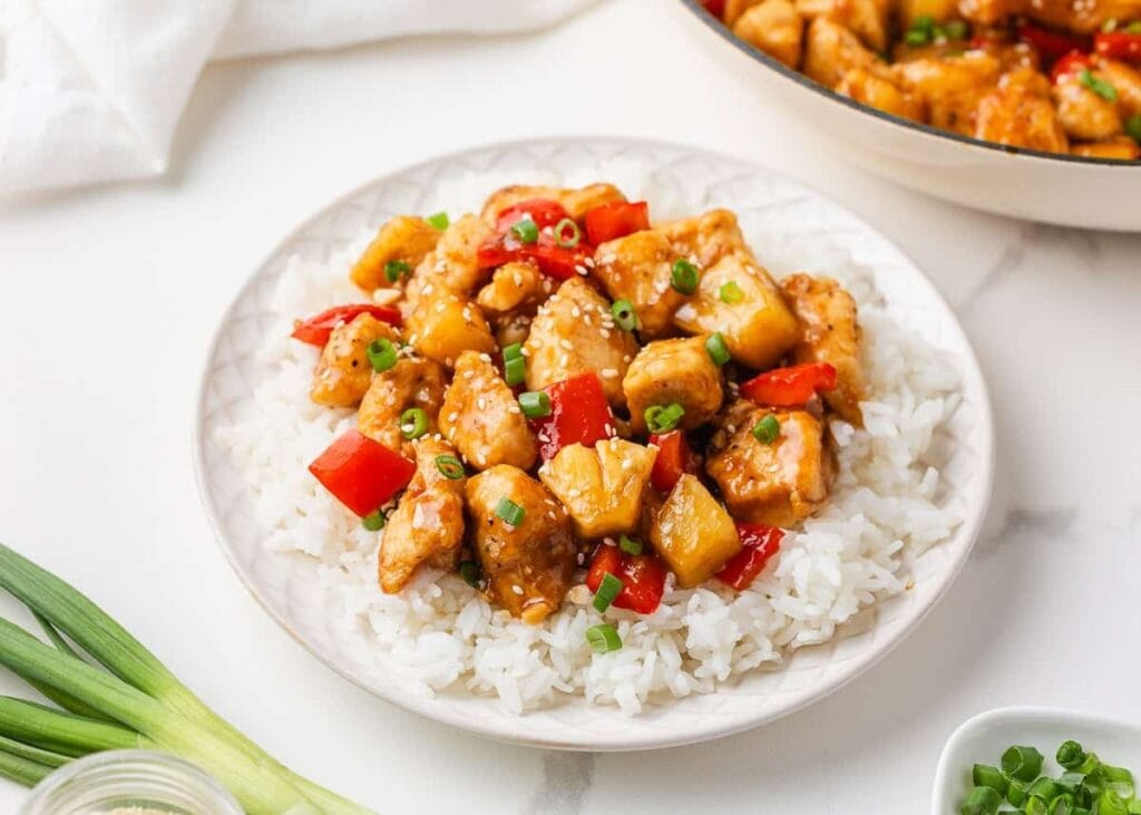 Pineapple chicken with rice on a plate.